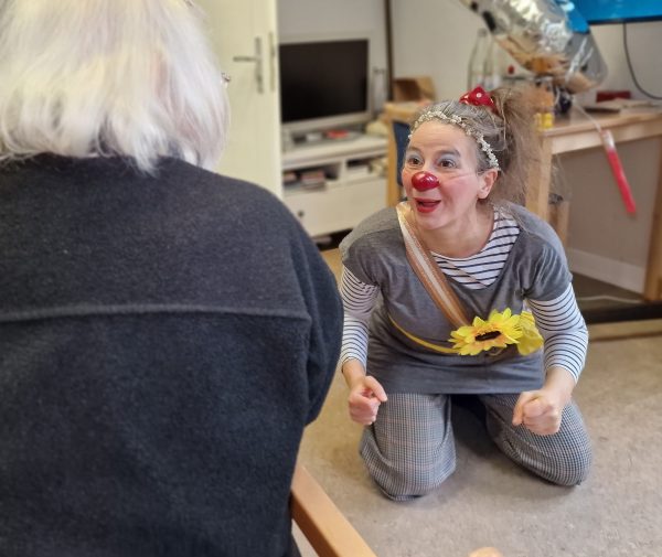 Clown hospitalier professionnel en train de faire rire une cliente.