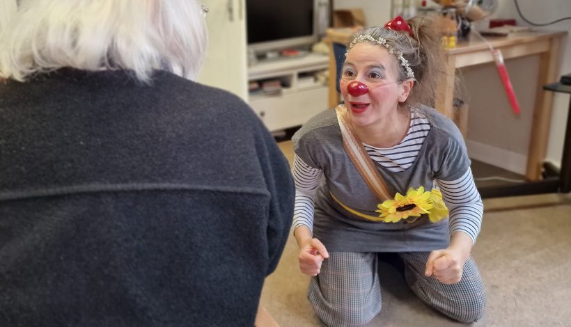 Clown hospitalier professionnel en train de faire rire une cliente.